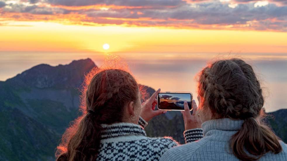 Two women taking picture of sunset